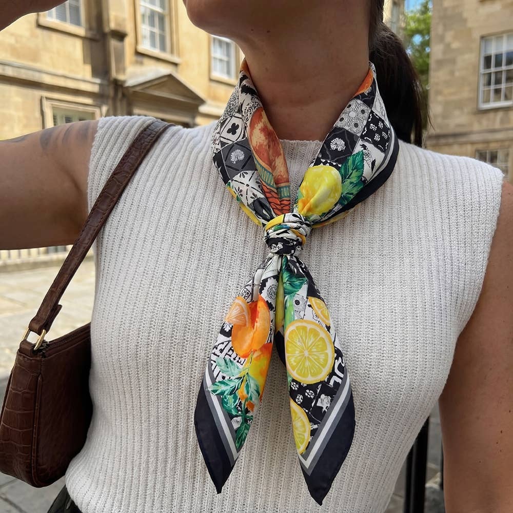 Person wearing a colorful fruit-patterned scarf with a building in the background