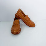 A pair of tan leather penny loafers with brown soles, displayed on a clean white studio background.