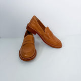A pair of tan leather penny loafers with brown soles, displayed on a clean white studio background.
