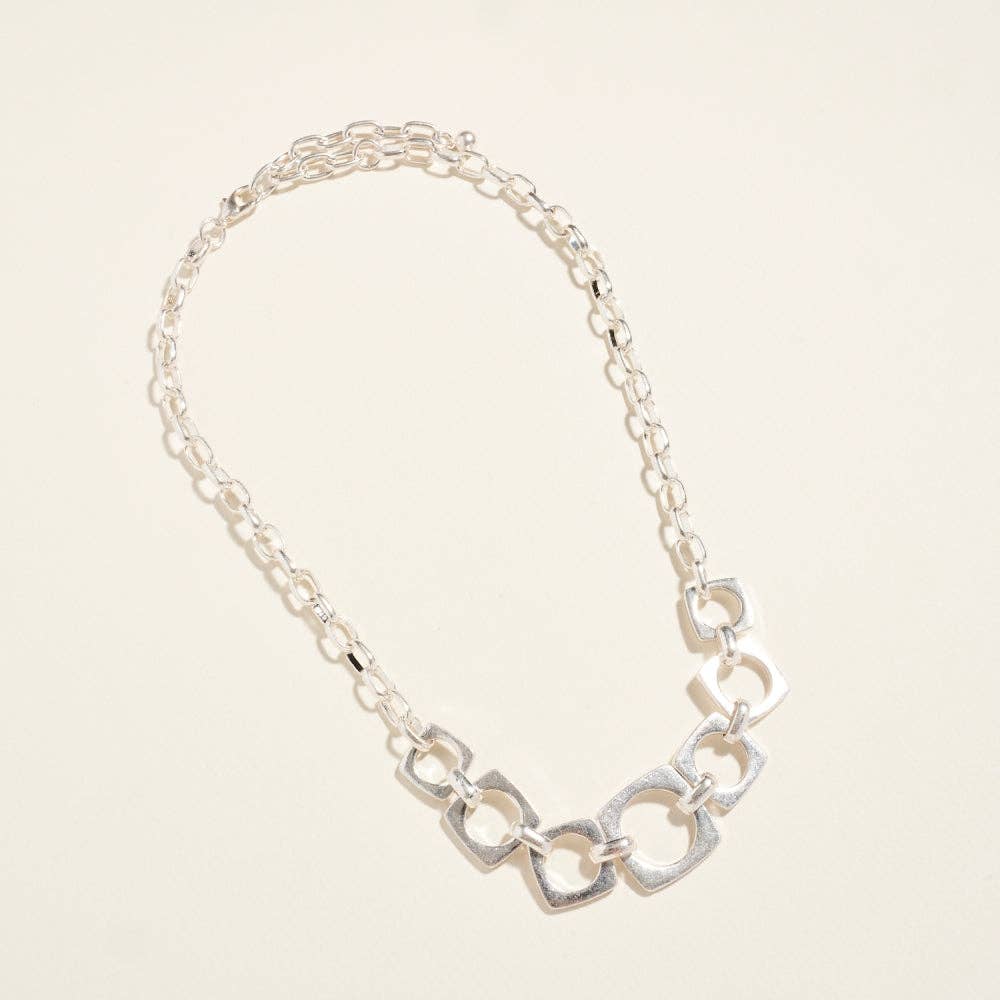 Silver chain necklace on a light beige background