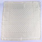 Beige fabric square with white polka dots on a light purple background