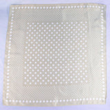 Beige fabric square with white polka dots on a light purple background