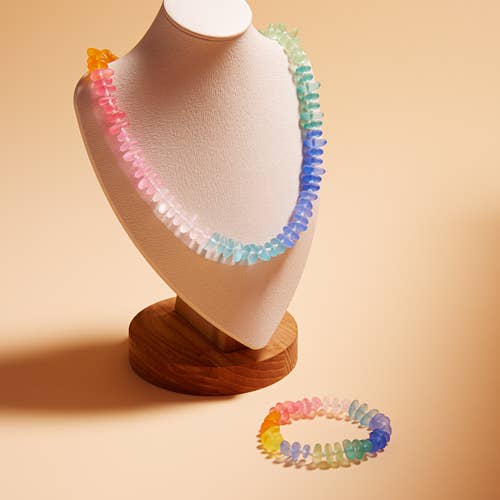 Colorful beaded necklace on a mannequin bust with a matching bracelet on a beige background
