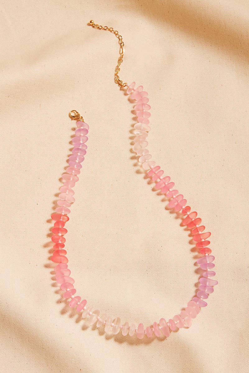 Necklace with pink and red beads on a beige background
