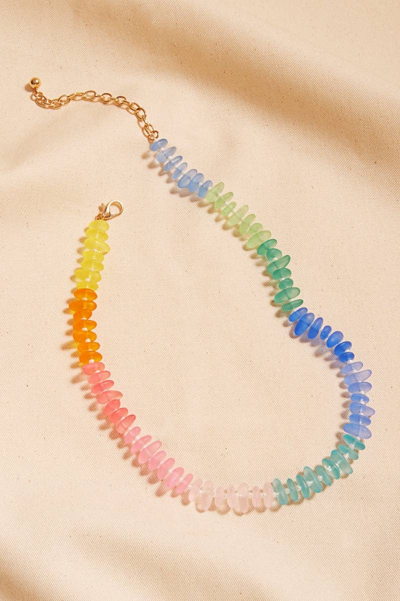 Necklace with multicolored beads on a beige fabric background