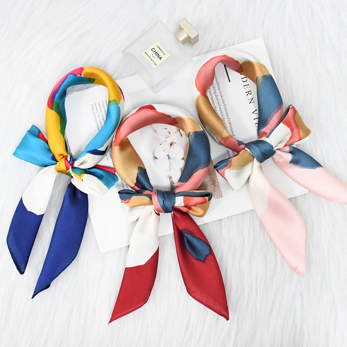 Colorful scarves tied into bows on a white surface with a visible brand name.
