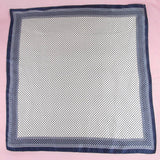 Navy blue and white patterned square scarf on a pink background
