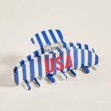 Blue and white striped hair clip with 'USA' lettering on a beige background