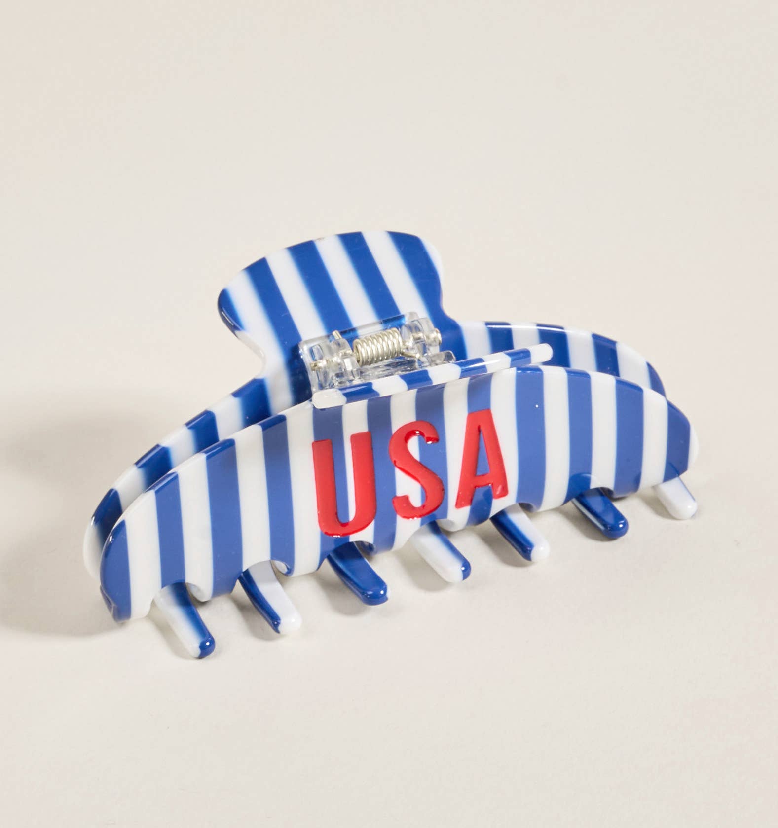 Blue and white striped hair clip with 'USA' lettering on a beige background