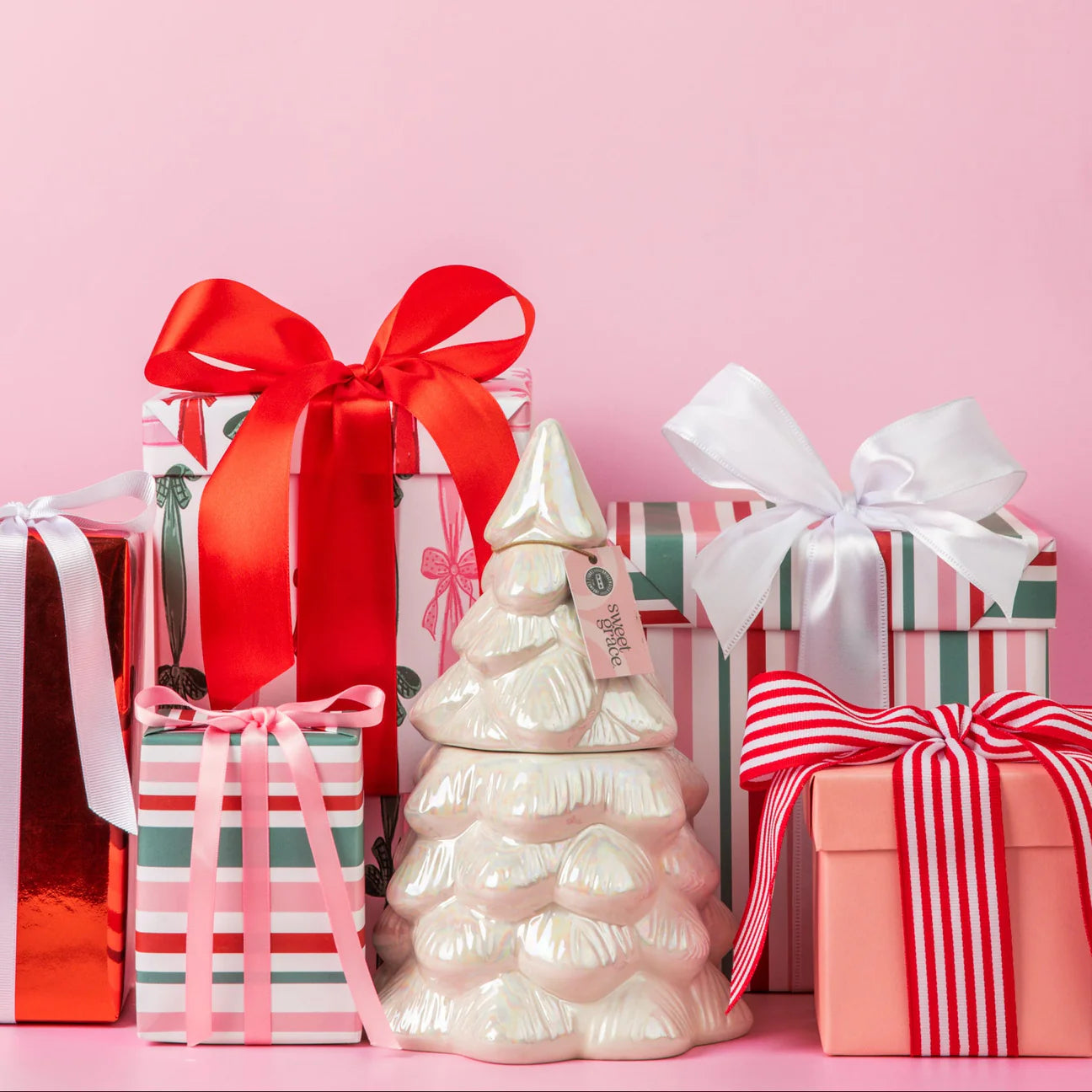 Decorative Christmas tree with gift boxes on a pink background